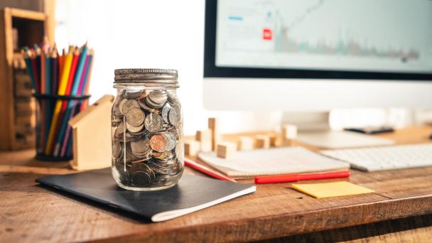 Money in a glass jar On the desk at home